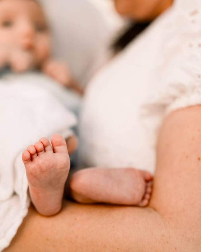 A newborn’s feet against her mother, close up