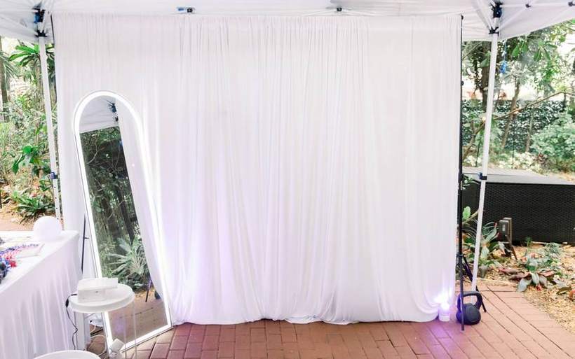 A draped backdrop with an LED arch mirror and uplighting