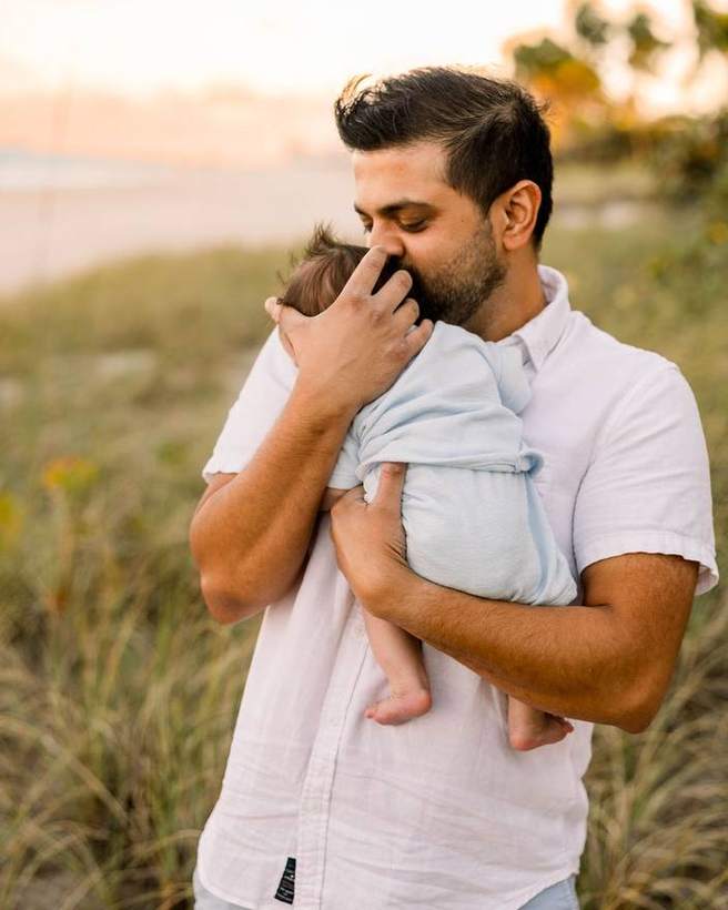 A father holding his newborn against the evening light