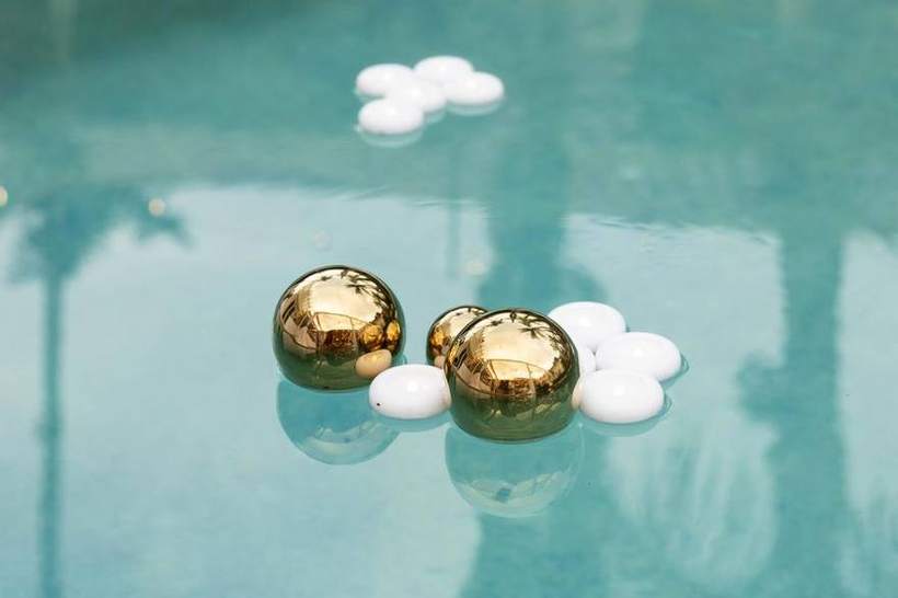 Gilded floating spheres in a pool at a reception