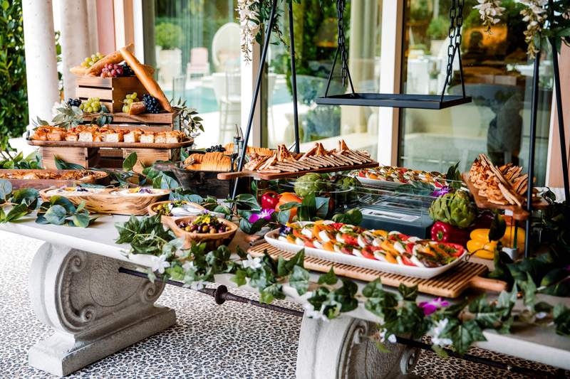 A grazing table of charcuterie and fruit built under greenery at a wedding