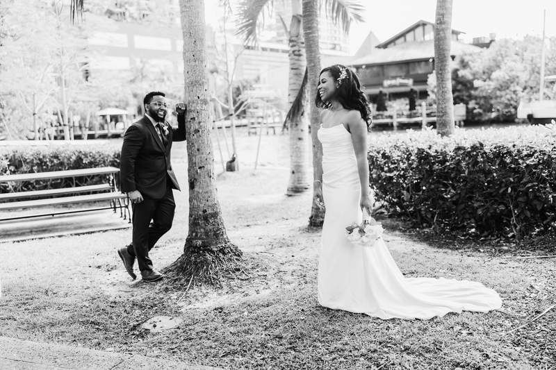 Black and white, a bride and groom walking beneath palm trees