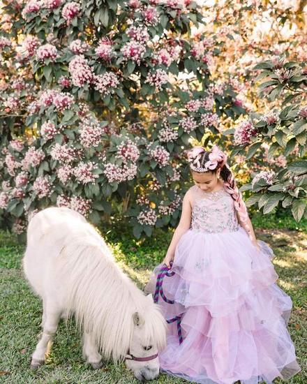 A child and a grazing pony beneath pink blossom
