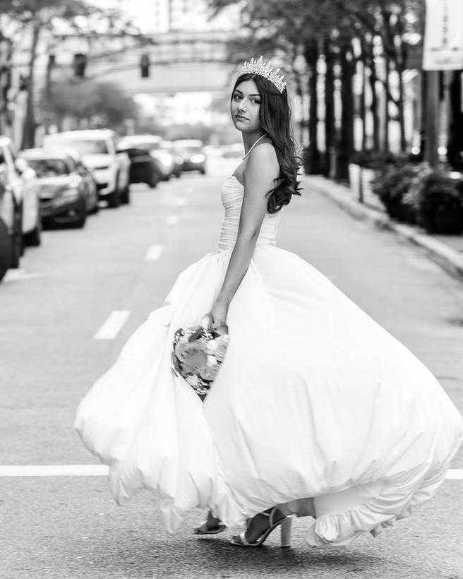 A quinceanera turning in the street, in black and white
