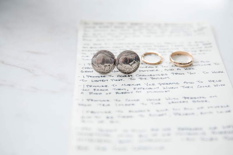 Handwritten wedding vows on paper with both rings resting on top