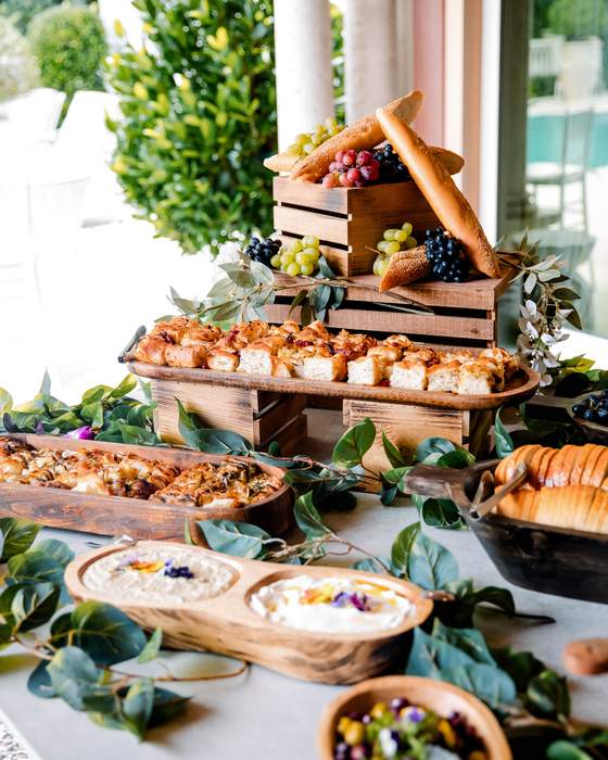 Crates of fruit, bread and canapes on a grazing table dressed with greenery