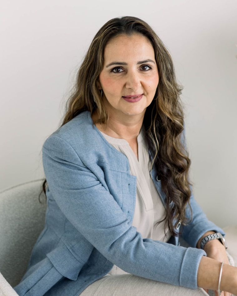 A personal branding headshot of a business owner in a pale blue blazer, shot in a bright white studio