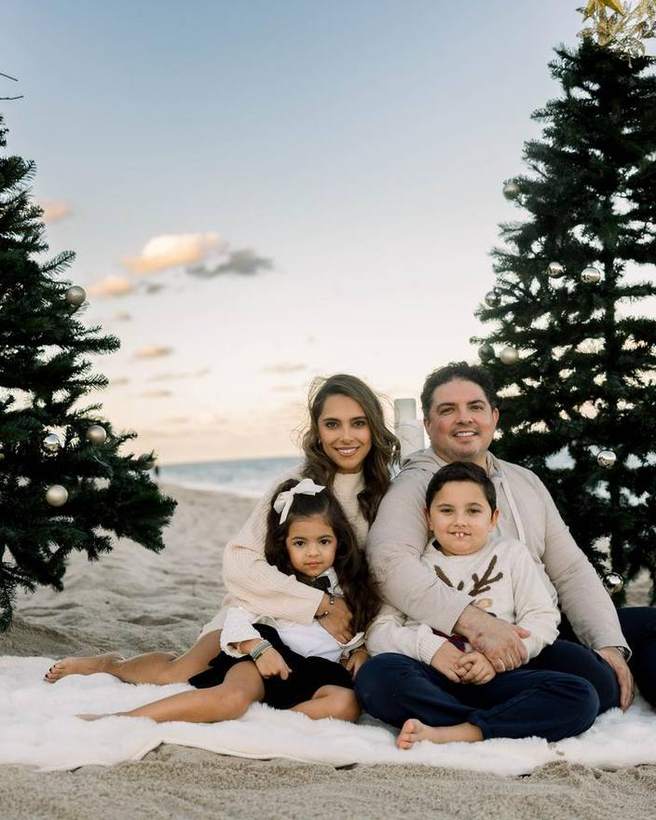 A family photographed together on the sand at a seasonal mini session