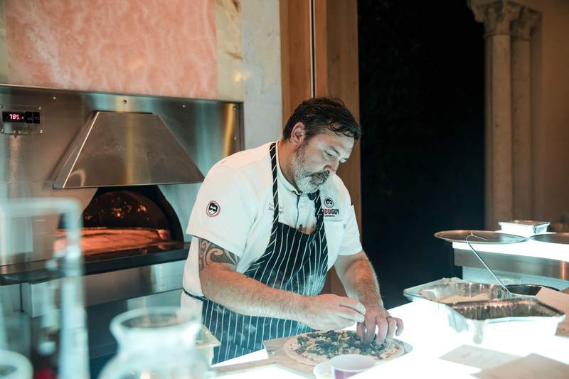 A chef plating at a wood fired oven during a wedding reception