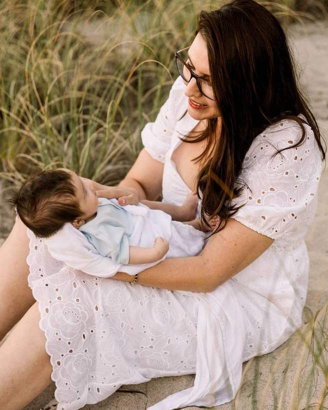 A mother holding her baby on the sand at sunset