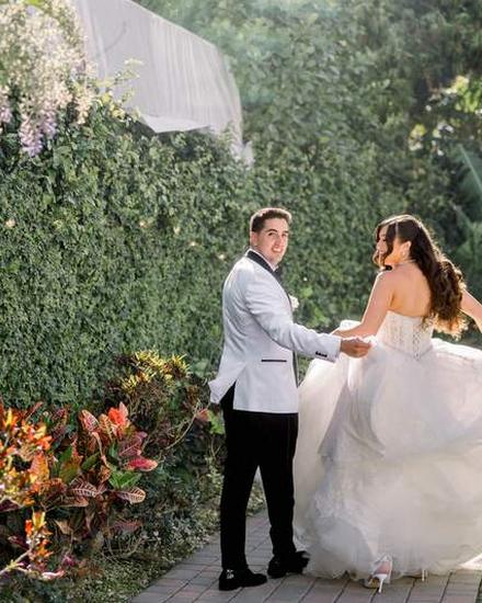 A bride and groom in a tropical garden, her veil lifting in the wind