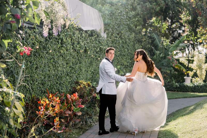 A bride and groom in a tropical garden, her veil lifting in the wind