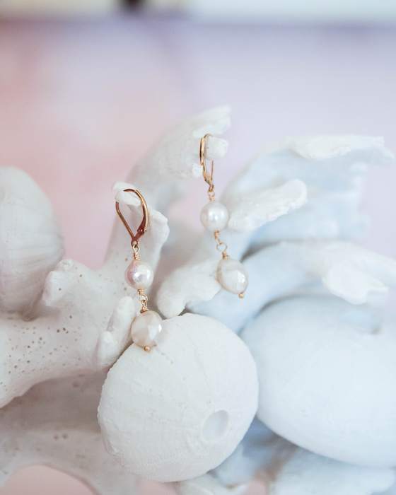 Pearl drop earrings resting on a white sculpture