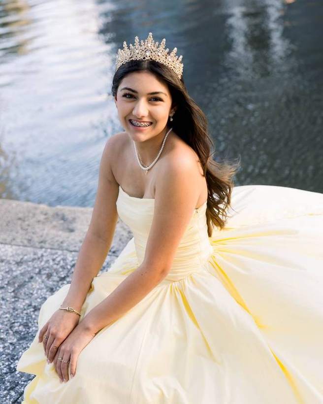A quinceanera by the water in her gown and crown