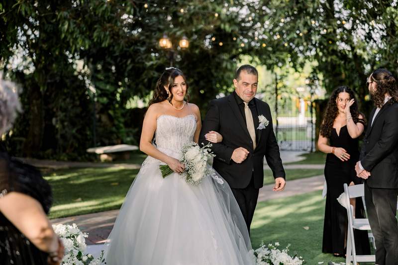 A bride walking down a garden aisle on her father's arm