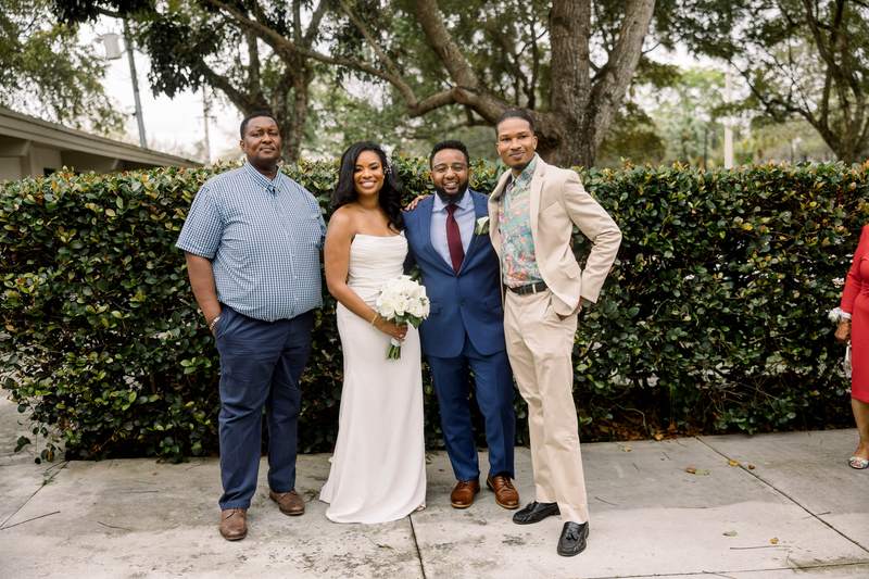 A bride and groom photographed with two guests outside after the ceremony
